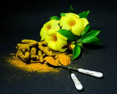 A composition of turmeric and yellow flowers on a black background