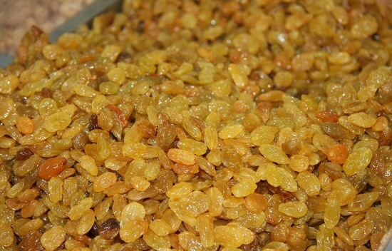 A close-up of a pan brimming with raisins, resting on a table.