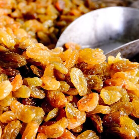 metal scoop in a pile of rich and juicy golden raisins