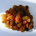 A close up of a pile of orange dried raisins.